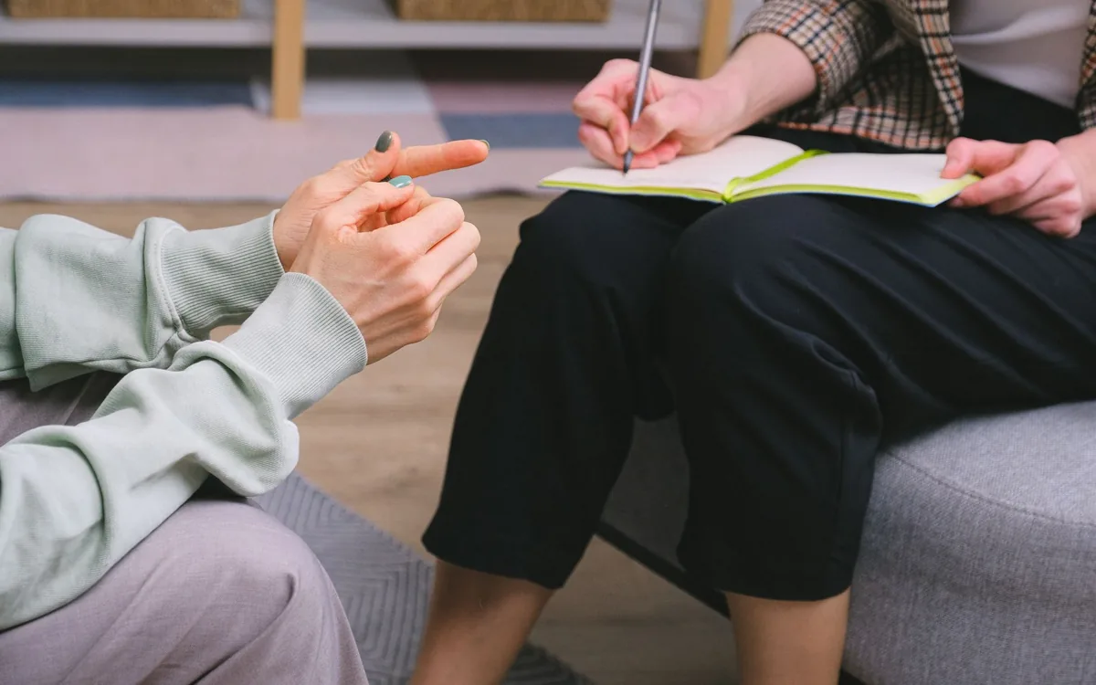 Sessão de psicoterapia com terapeuta anotando durante a conversa